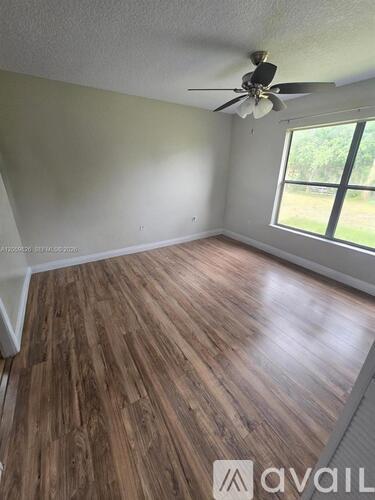 A room with wooden flooring and a ceiling fan.