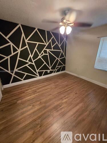 A room with wooden flooring and a black and white geometric wallpaper.