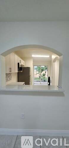 A modern kitchen with white cabinets and a large window.