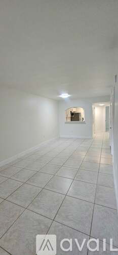 A spacious room with white walls and tiled flooring.