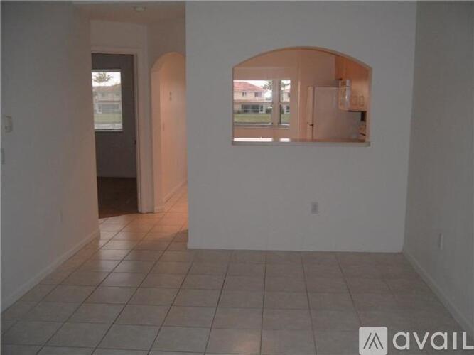 A room with white walls and a tiled floor with a doorway leading to another room.