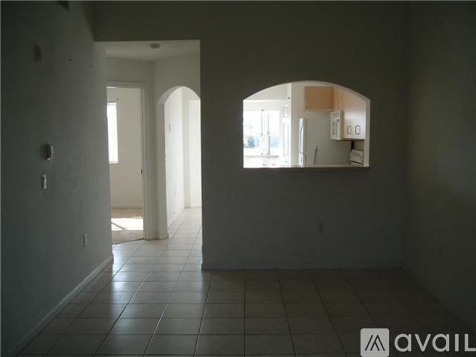 A room with a tiled floor and a mirror reflecting a kitchen.