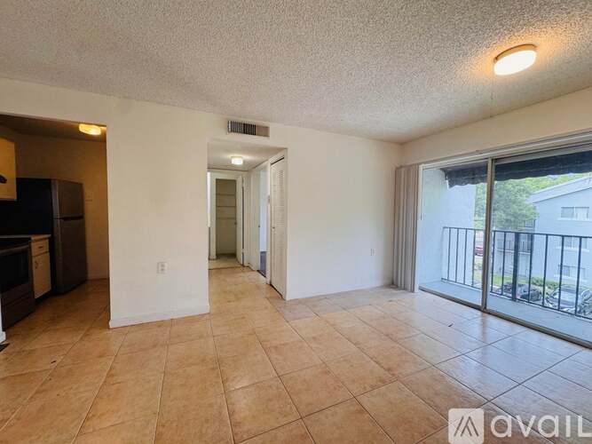 A spacious living room with tiled flooring and sliding glass doors leading to a balcony.
