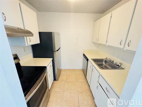 A kitchen with white cabinets and a black refrigerator.