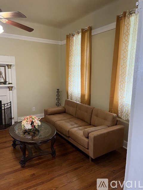 A living room with a brown couch and a glass table with flowers on it.