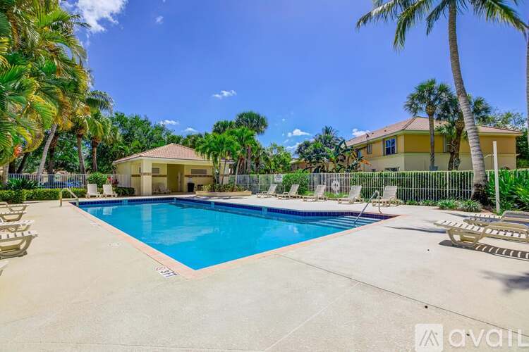 A pool surrounded by palm trees and a house in the background.