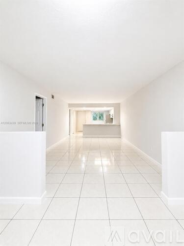 A white room with a tiled floor and a door on the left.