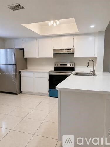 A kitchen with white cabinets and a stainless steel refrigerator.