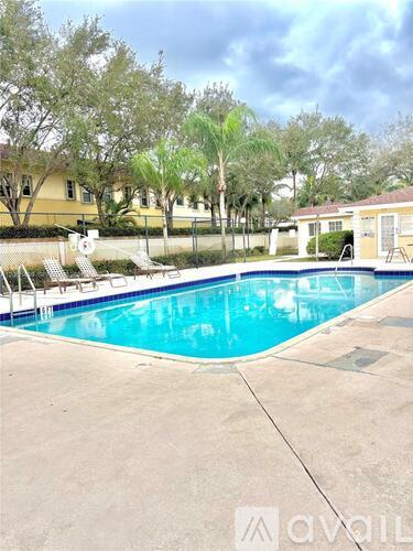 A swimming pool surrounded by trees and a building in the background.