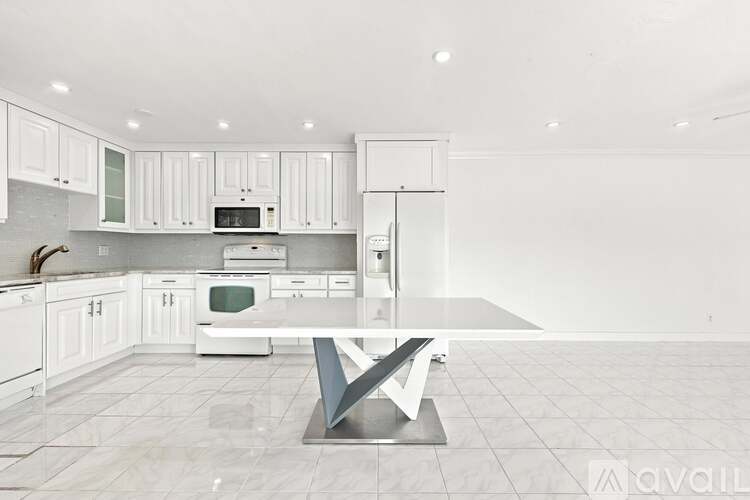 A kitchen with white cabinets and a large island in the middle.