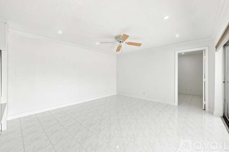 A spacious room with a ceiling fan and white walls.