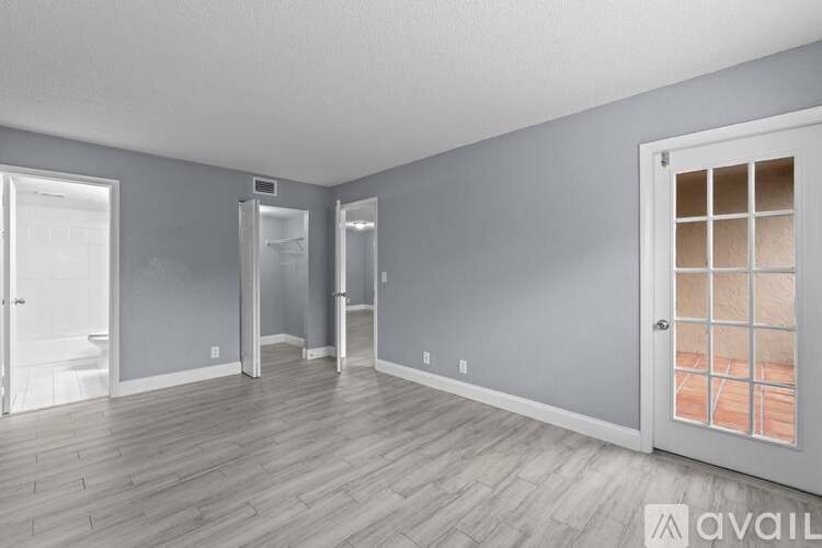A room with grey walls and wooden flooring, with a door on the right side.
