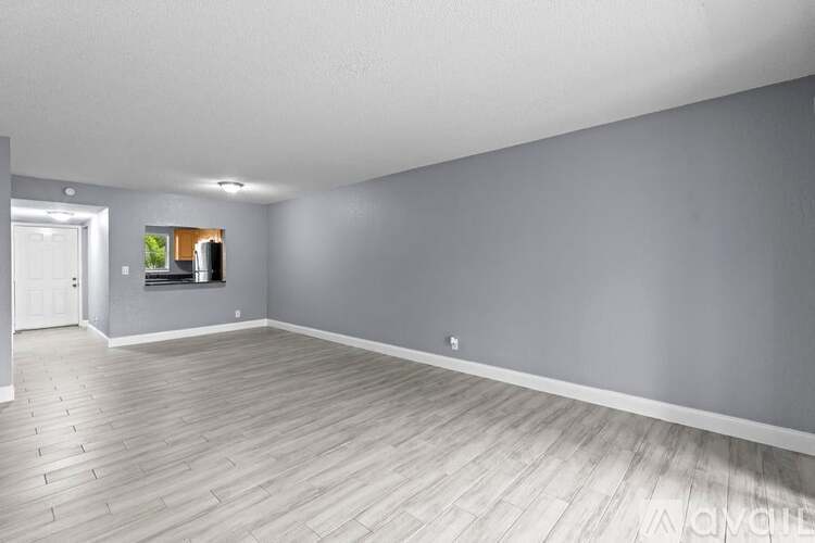 A spacious room with wooden flooring and a white door.