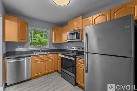 A kitchen with wooden cabinets and a stainless steel refrigerator.