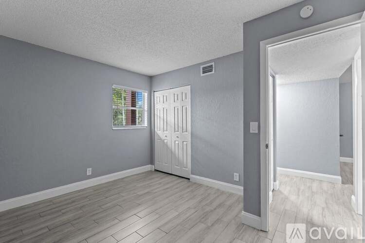 A room with a white door and a window with a view of a building outside.