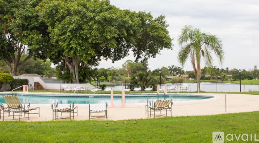 A pool surrounded by trees and chairs.