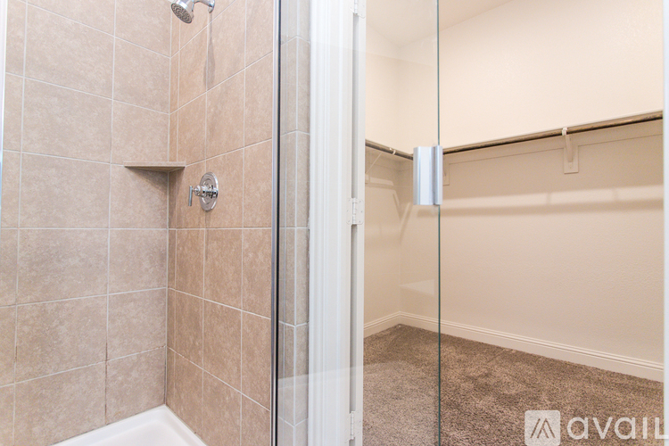 A bathroom with a walk-in shower and a glass door leading to a bedroom.