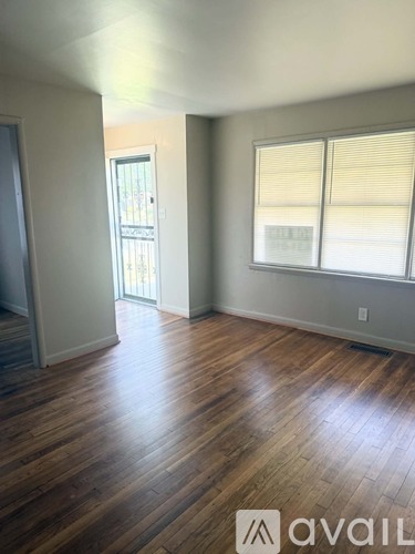 A room with wooden floors and a window with blinds.