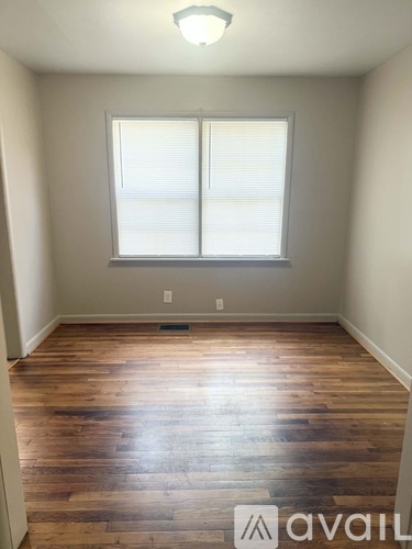 A room with wooden floors and a window with blinds.