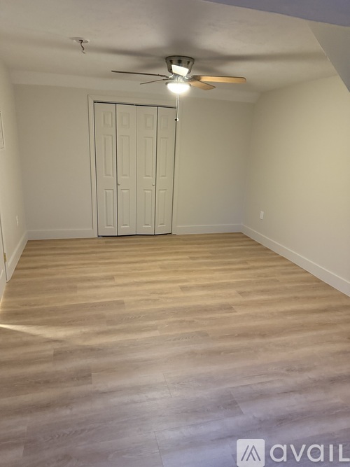A room with a white door and a ceiling fan.