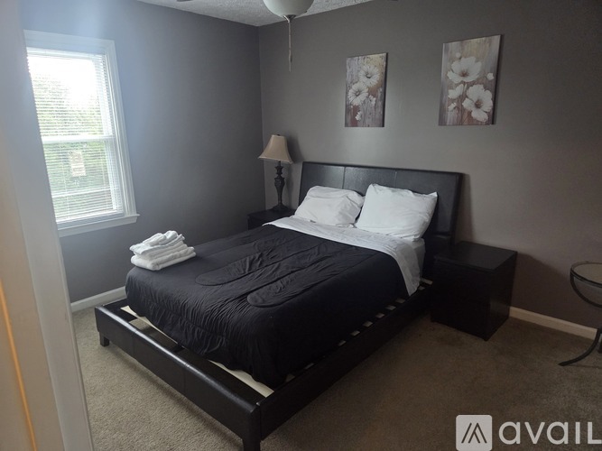A bedroom with a black bed and a lamp on the side table.