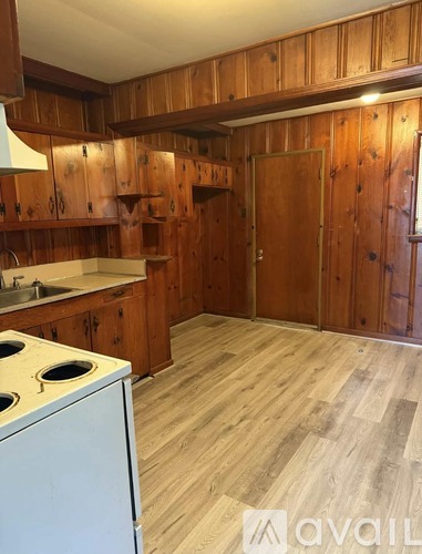 A kitchen with wooden cabinets and a white stove top oven.