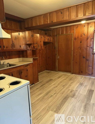 A kitchen with wooden cabinets and a white stove top oven.