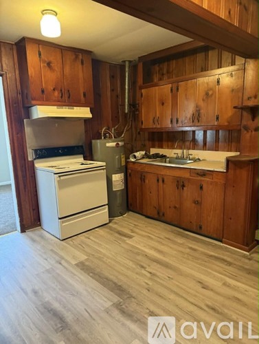 A kitchen with wooden cabinets and a white stove top oven.