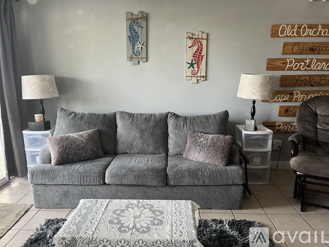 A grey couch with a grey rug in front of it.