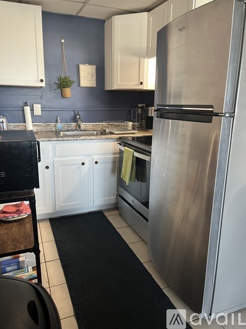 A kitchen with a stainless steel refrigerator and white cabinets.