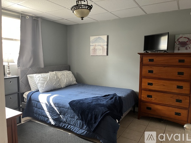 A bedroom with a bed, dresser, and window.