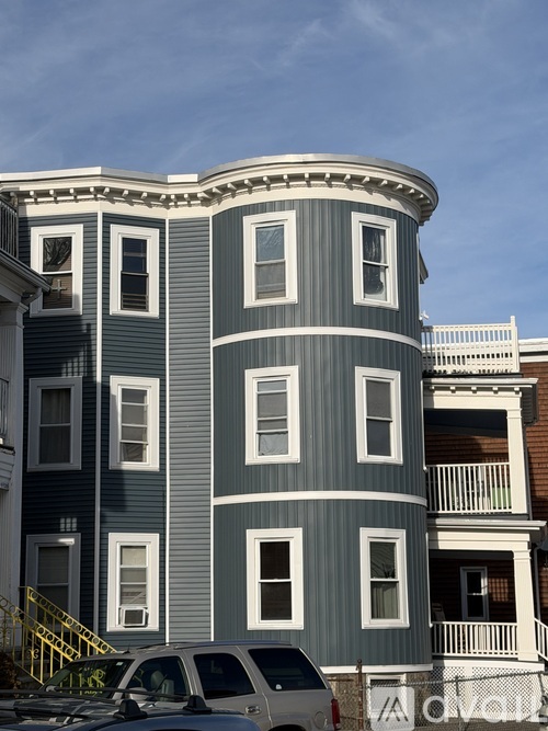 A grey building with white trim and a car parked in front.