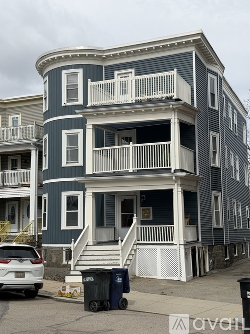 A two-story house with a white balcony and a grey exterior.