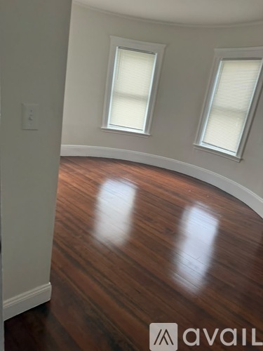 A room with wooden floors and two windows.