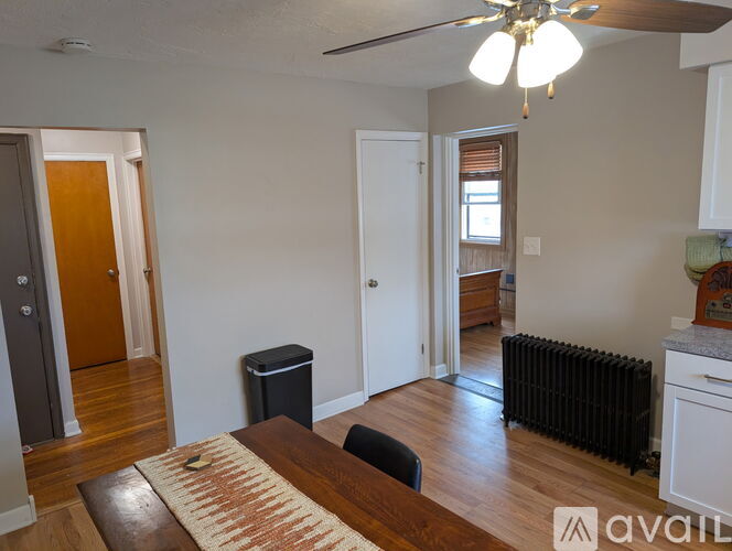A living room with a brown rug and a black trash bin.