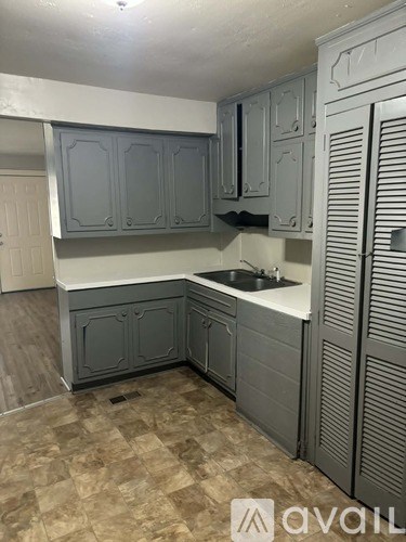 A kitchen with grey cabinets and a white countertop.