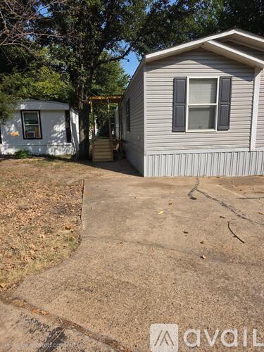 A mobile home with a concrete walkway leading to the front door.