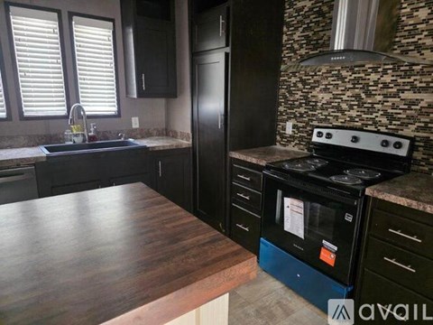 A kitchen with a black refrigerator and a wooden countertop.