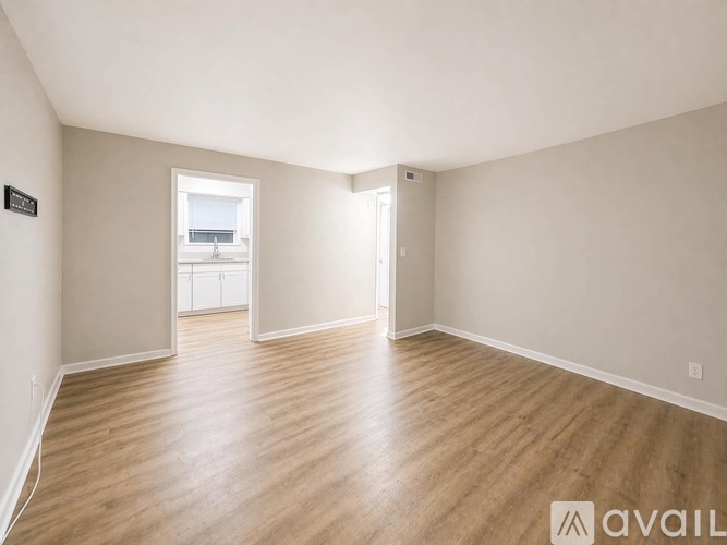A spacious room with wooden flooring and white walls.