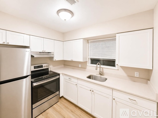 A kitchen with white cabinets and a stainless steel refrigerator.