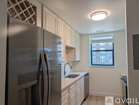 A kitchen with a stainless steel refrigerator and wooden cabinets.