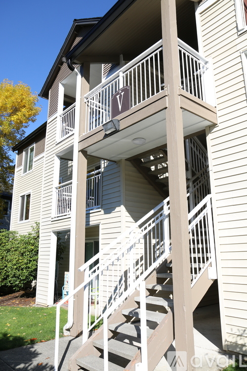 A white staircase leads to a balcony on the second floor of a building.