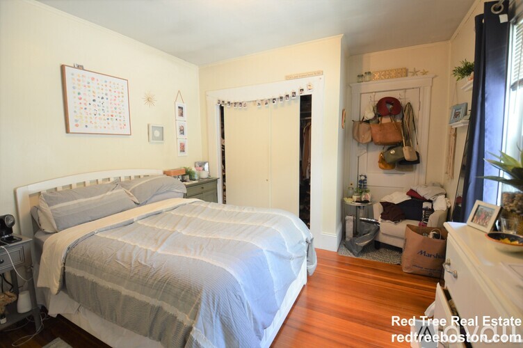 A bedroom with a bed, nightstand, and a calendar on the wall.