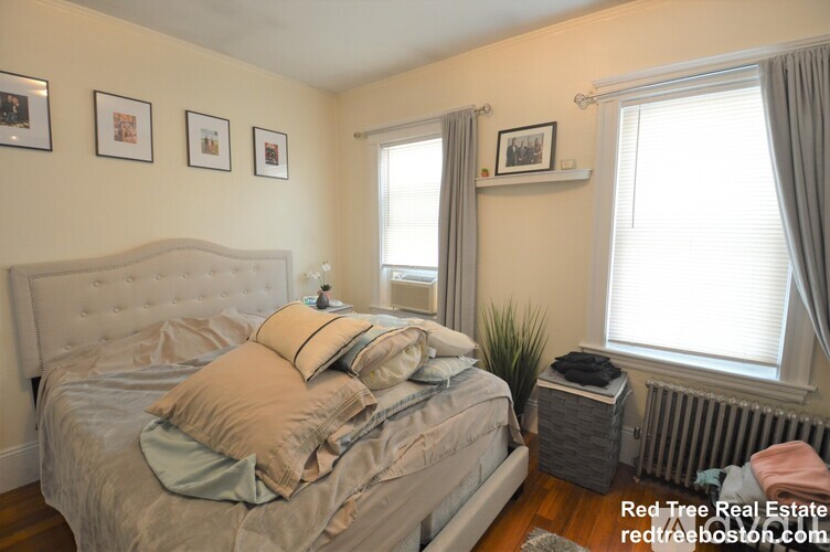 A bedroom with a large bed and a window with curtains.