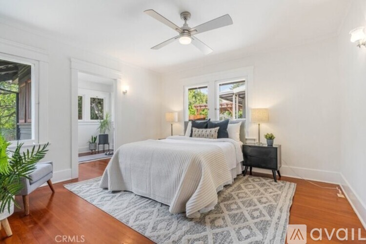 A bedroom with a bed, nightstand, and a plant.