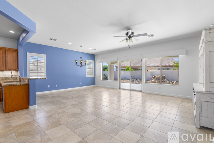 A spacious living room with a ceiling fan and a view of the outdoors through the sliding glass doors.