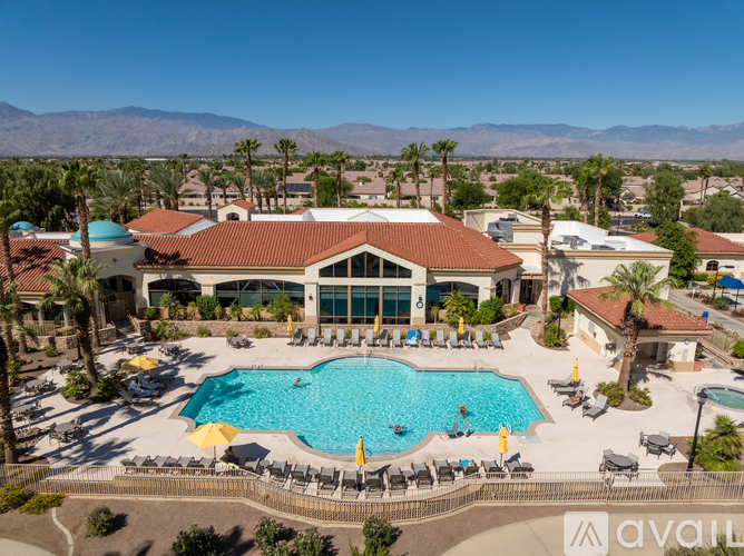 A large outdoor swimming pool surrounded by sun loungers and umbrellas.