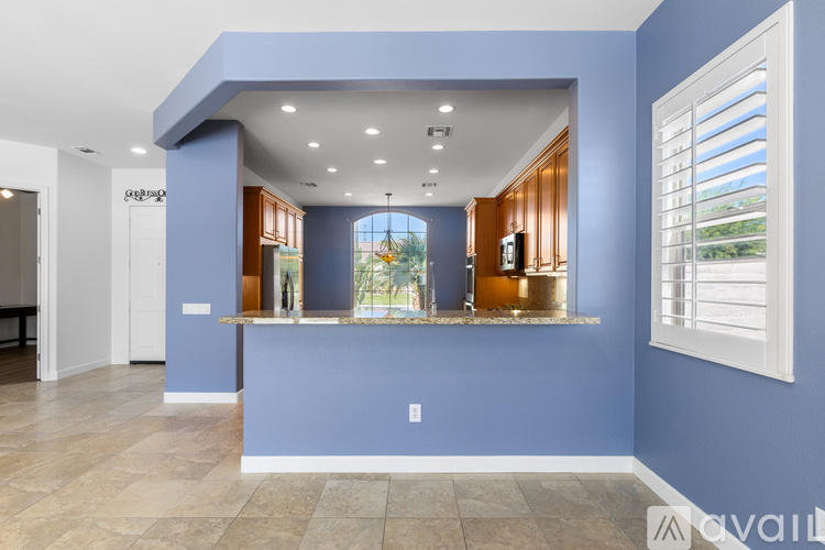 A spacious room with a blue wall and a window with blinds.