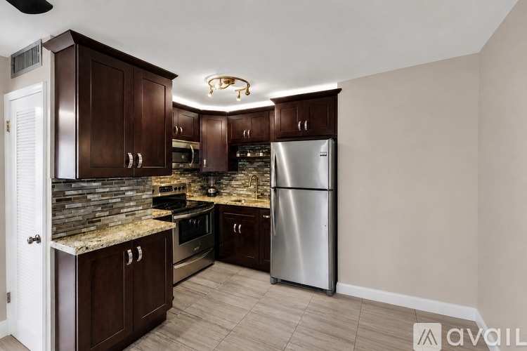 A kitchen with wooden cabinets and a stainless steel refrigerator.