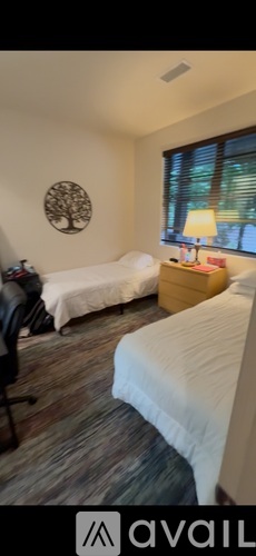 A bedroom with two beds and a desk with a lamp.